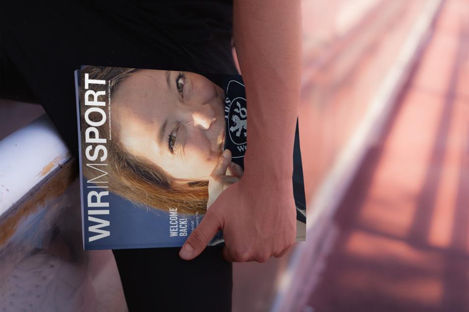Nahaufnahme einer Person, die ein Sportmagazin mit dem Titel &bdquo;WIR SPORT&ldquo; in der Hand h&auml;lt.